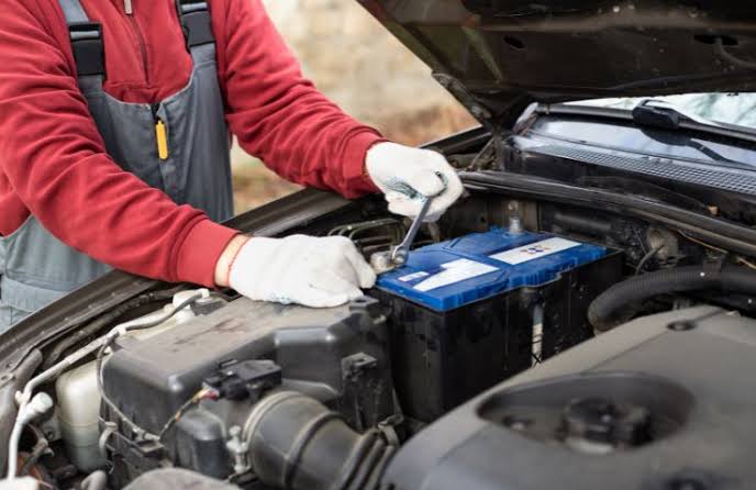 Technician performing car battery replacement service in UAE workshop